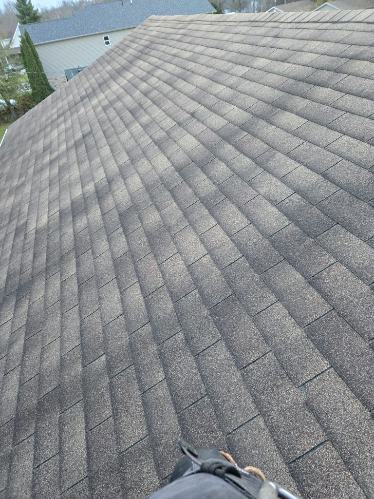 Close-up of weathered 3-tab shingles with heavy degranulation and curling edges on a residential roof