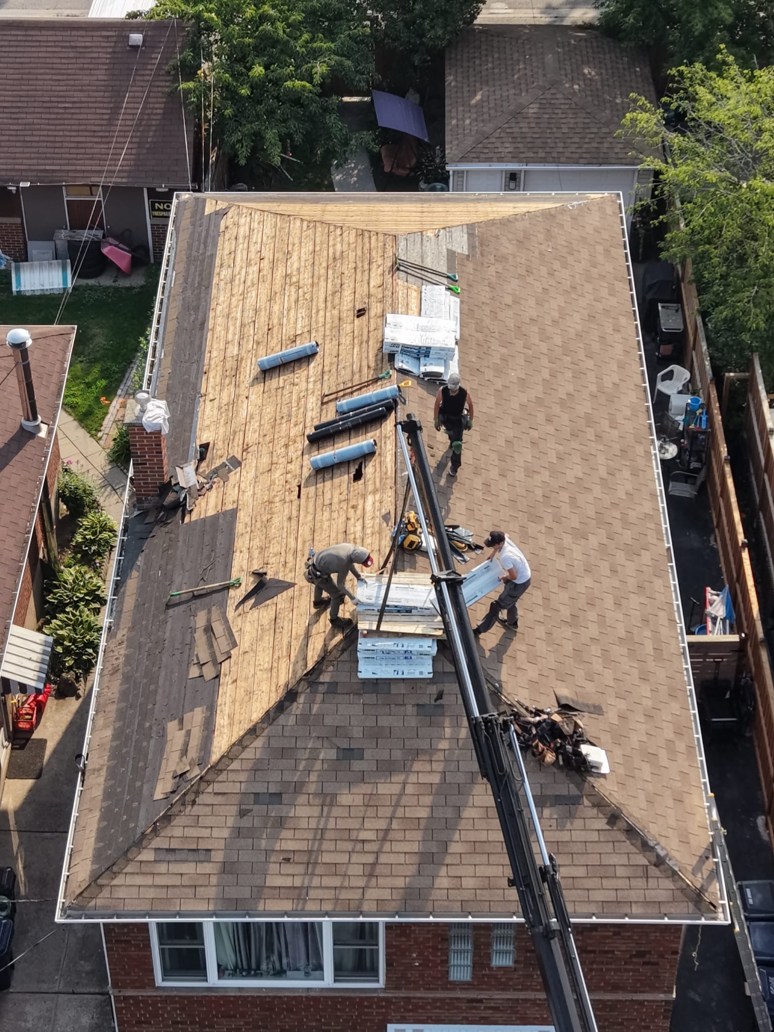 Dark brown standing seam metal roof panels being installed on a residential home in autumn